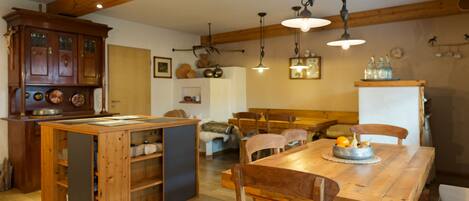 A dining area with a wooden table, chairs, and a cabinet with shelves.