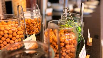Un buffet proposant une variété d’aliments présentés dans des récipients transparents, notamment des noix, des fruits secs et, éventuellement, quelques légumes.