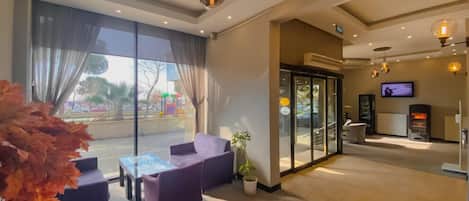 A hotel lobby with a seating area, a television, and a fireplace.