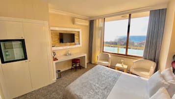 Habitación de hotel con cama, escritorio, silla, televisor y vista al mar.