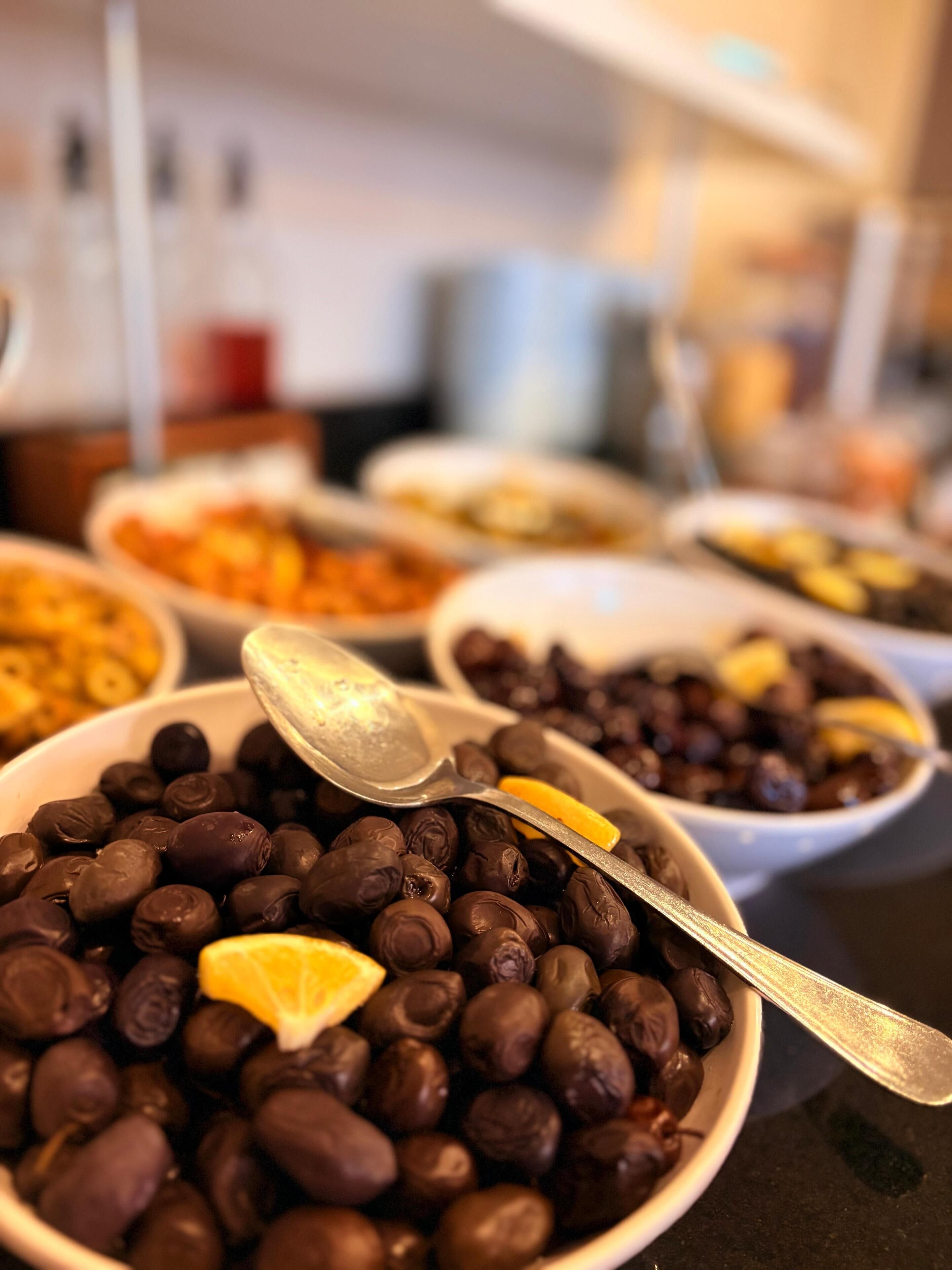 A variety of food items in bowls, including a bowl of chocolate-covered beans with a lemon slice on top.