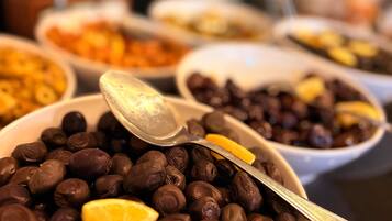 A variety of food items in bowls, including a bowl of chocolate-covered beans with a lemon slice on top.