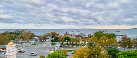Un paisaje costero con un puerto deportivo, una torre del reloj y vistas al mar.