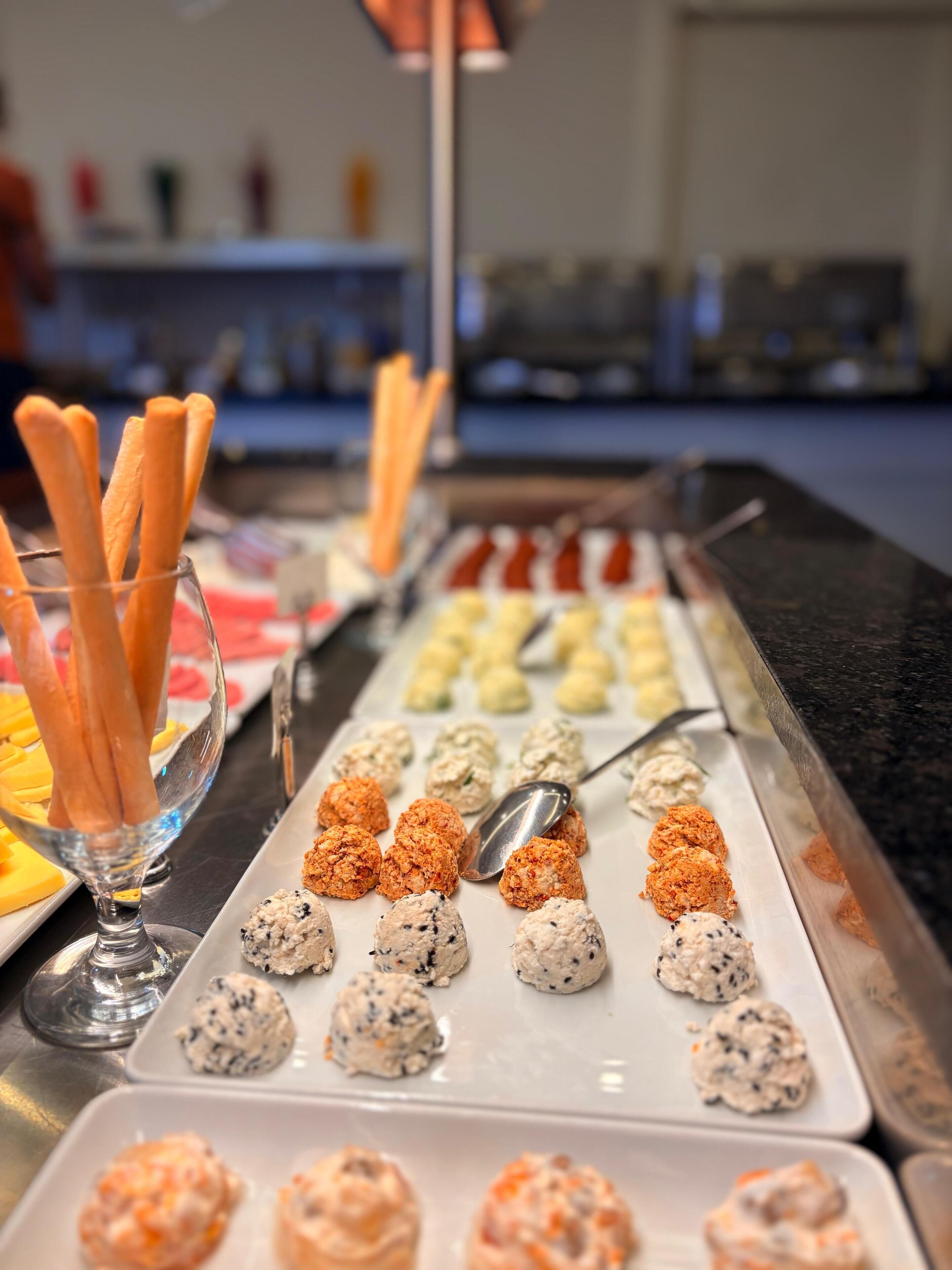 A buffet with various food items including breadsticks, meatballs, and different types of dips.