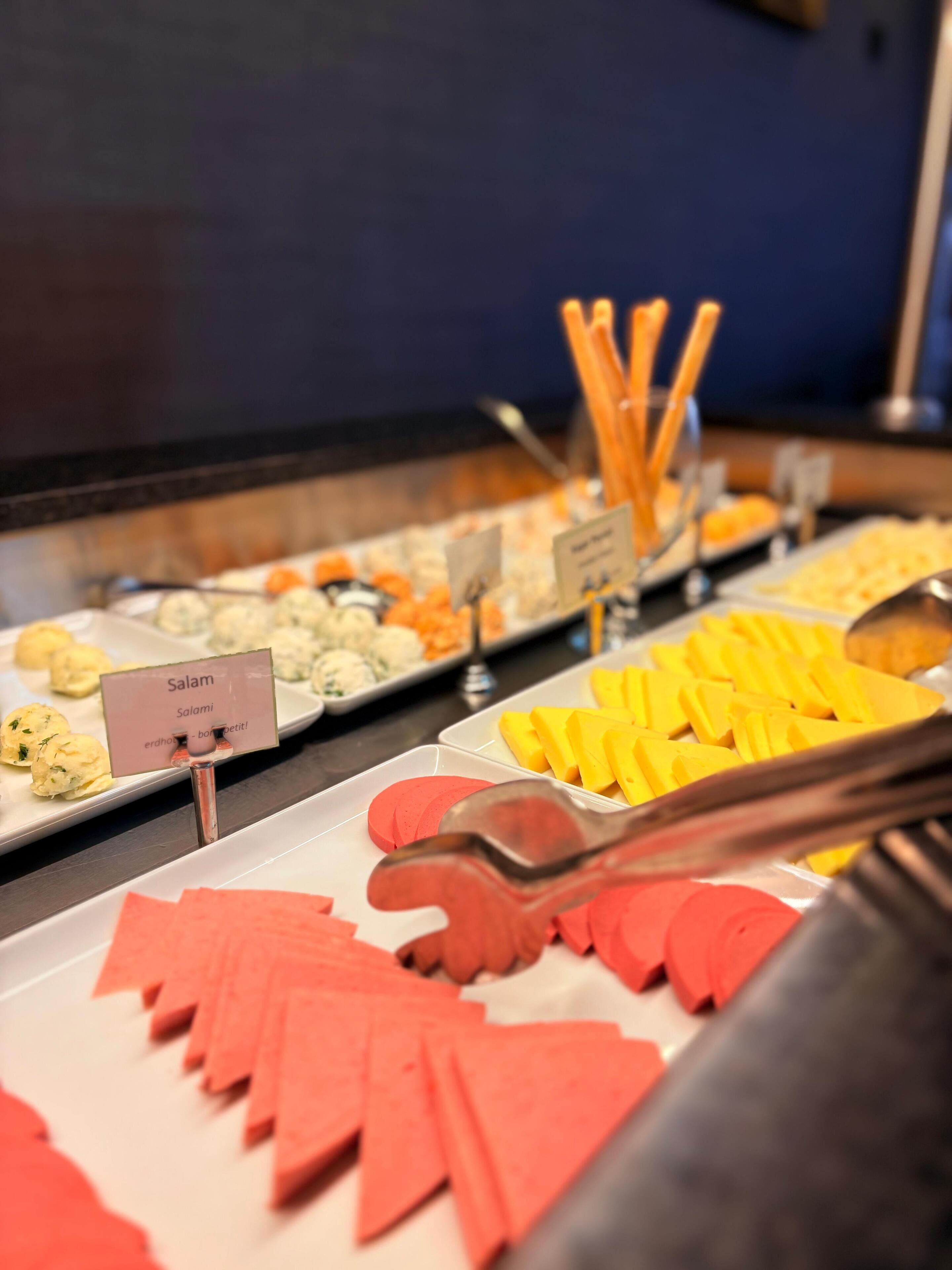 A buffet with various food items including salads, pasta, and bread.