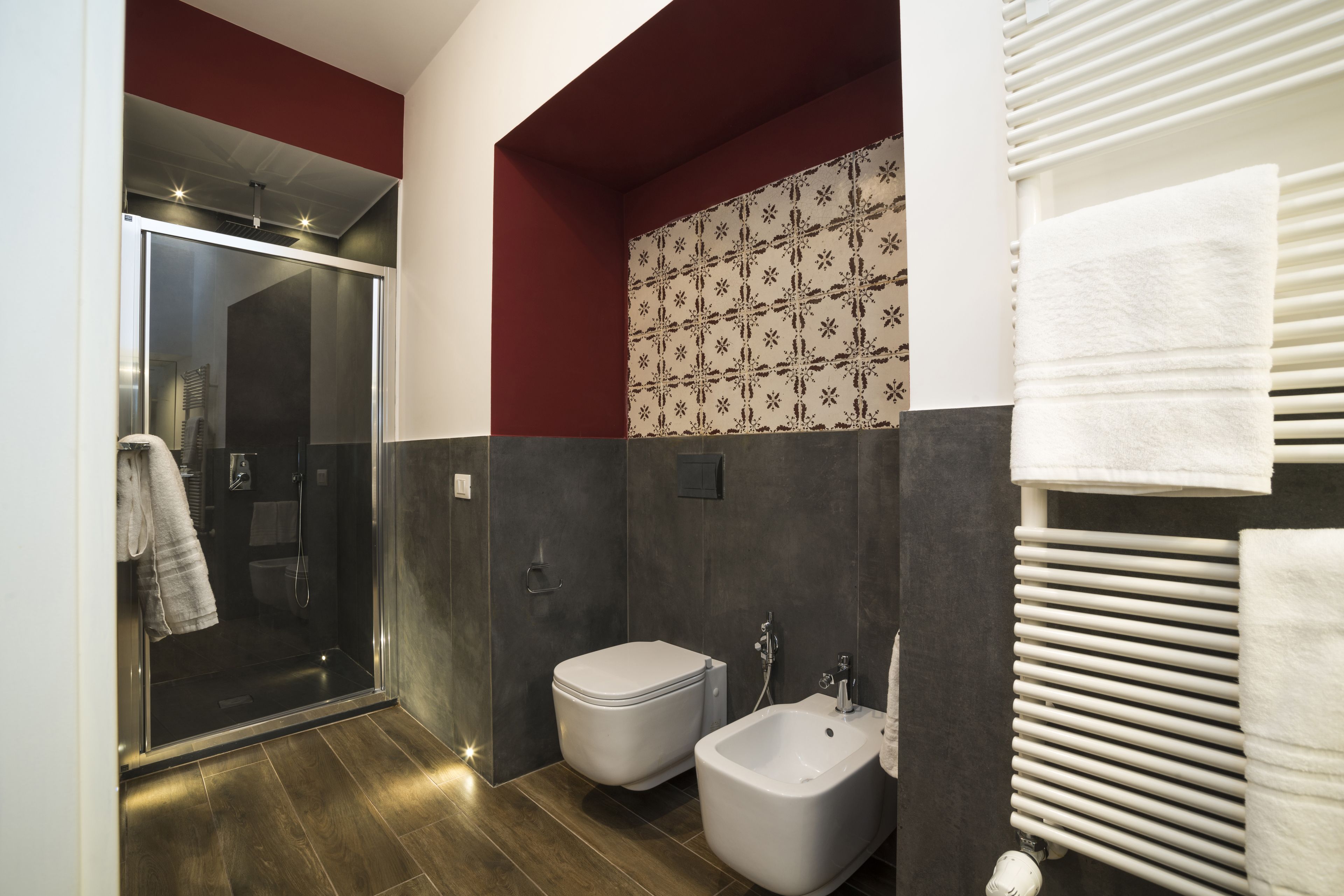 A modern bathroom with a glass shower enclosure, a bidet, and a towel rack.