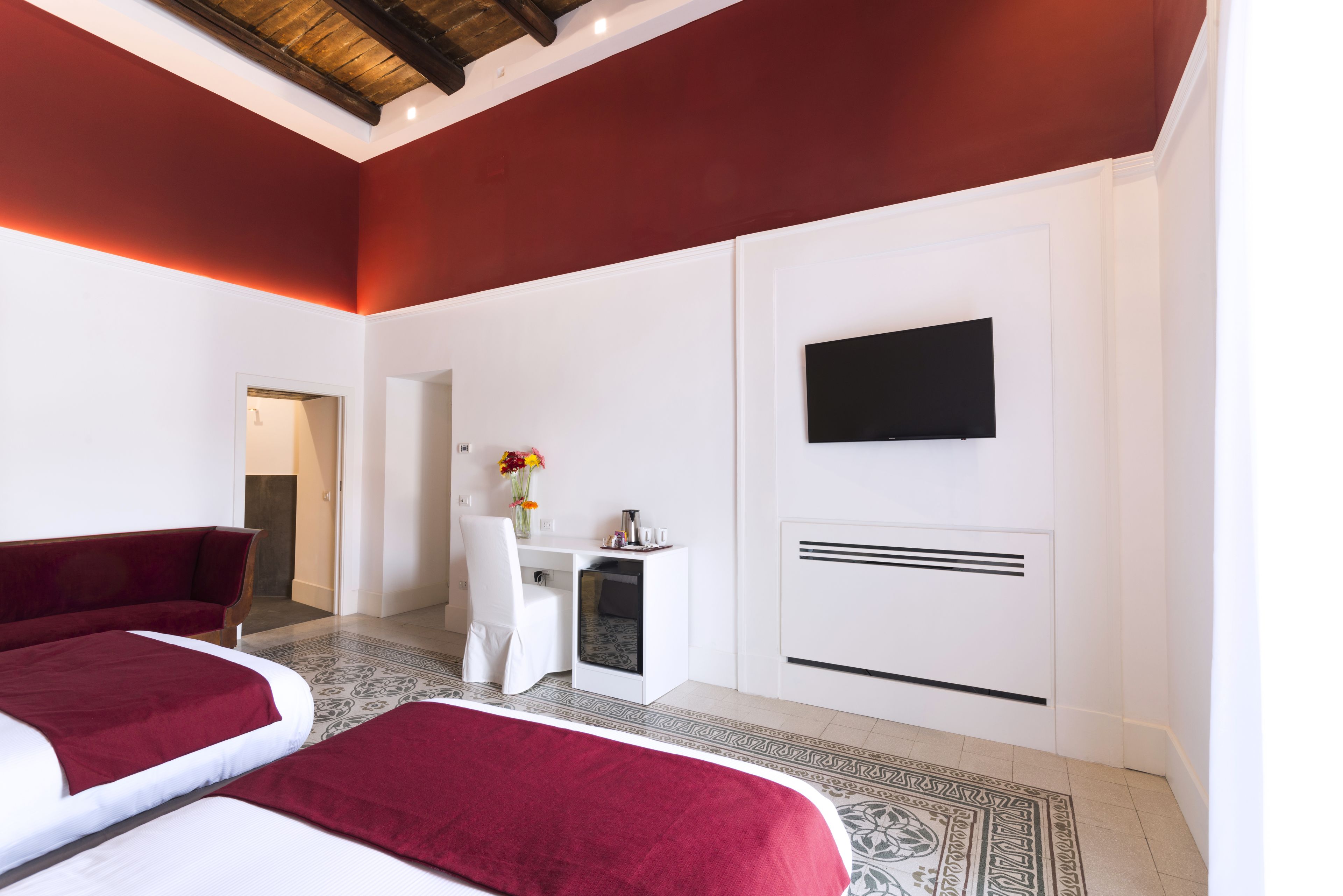 Habitación de hotel con dos camas, un escritorio, una silla, un televisor y una alfombra estampada.