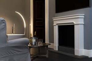 Een moderne woonkamer met een open haard, een aan de muur bevestigde televisie en een tafel met champagneflessen en glazen.