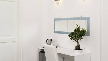 A bathroom with a white vanity, a mirror with a blue frame, a potted plant, and two wall-mounted lights.