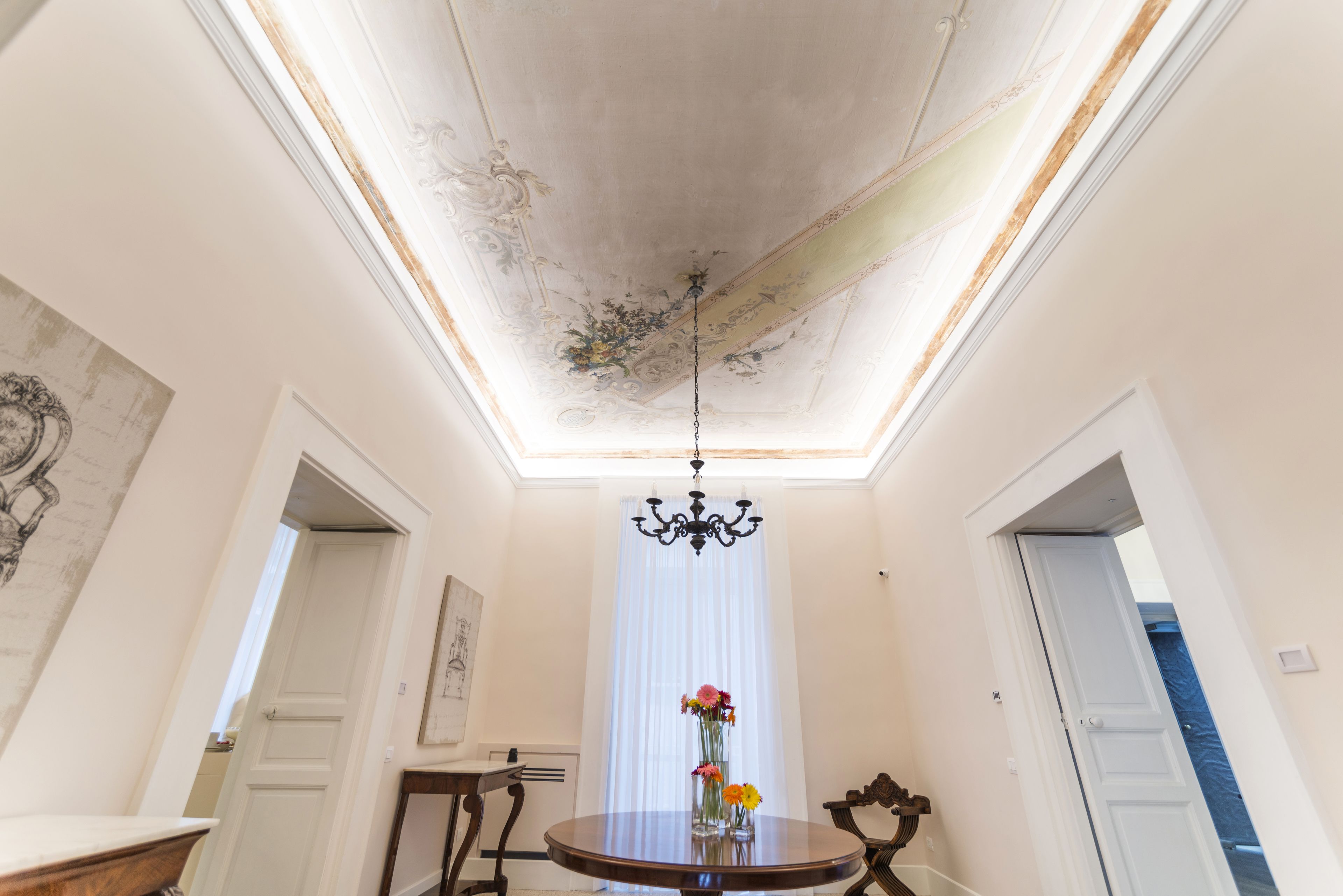 Een eetruimte met een kroonluchter, een ronde tafel en een vaas met bloemen.