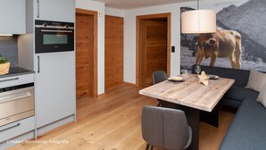 A modern kitchen with a built-in oven and a dining area with a wooden table and chairs. - AlpenNaturIdyll  (Grainau)