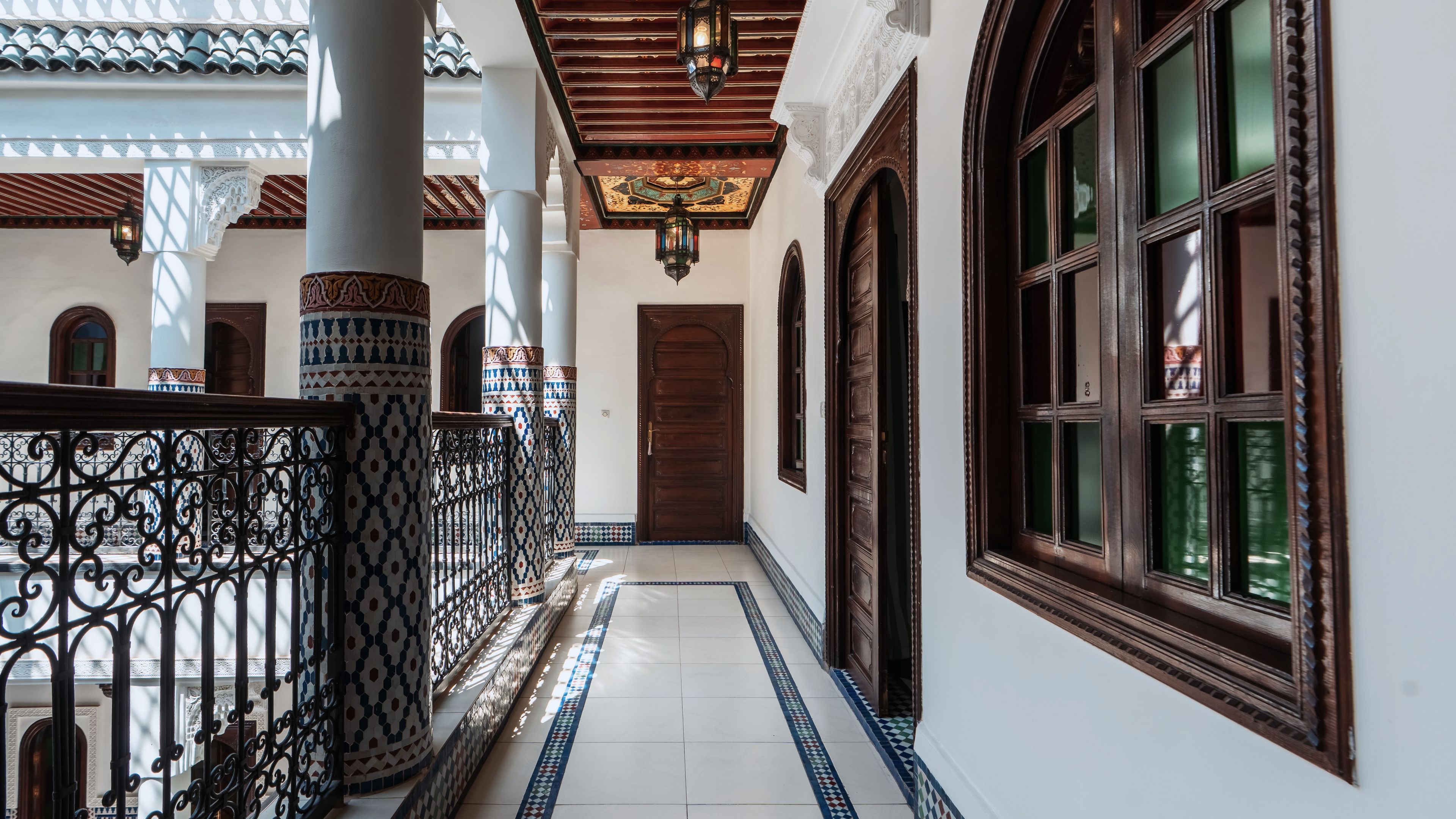 A corridor with patterned columns, a wooden door, and a window with a dark frame.