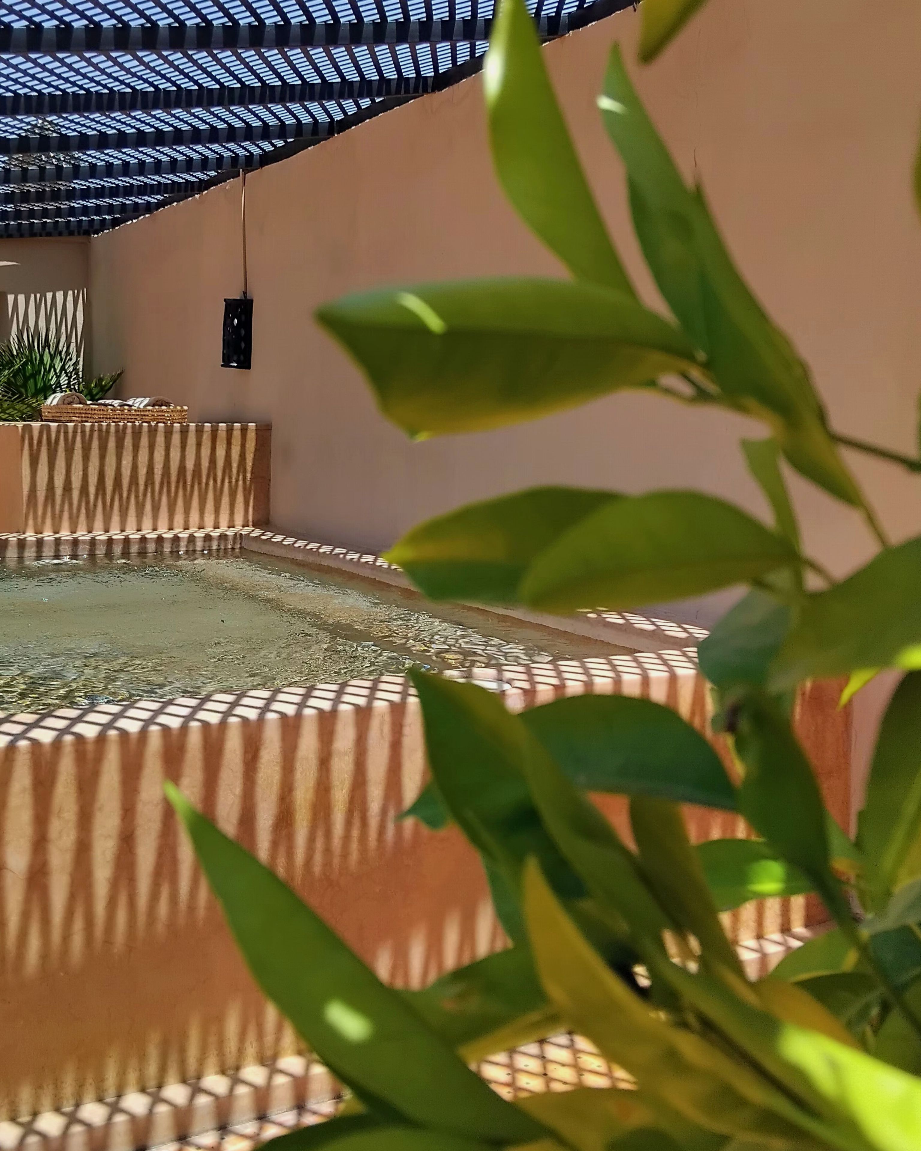 Ein Poolbereich mit Sonnenschirm, Liegestuhl und kleinem Tisch.