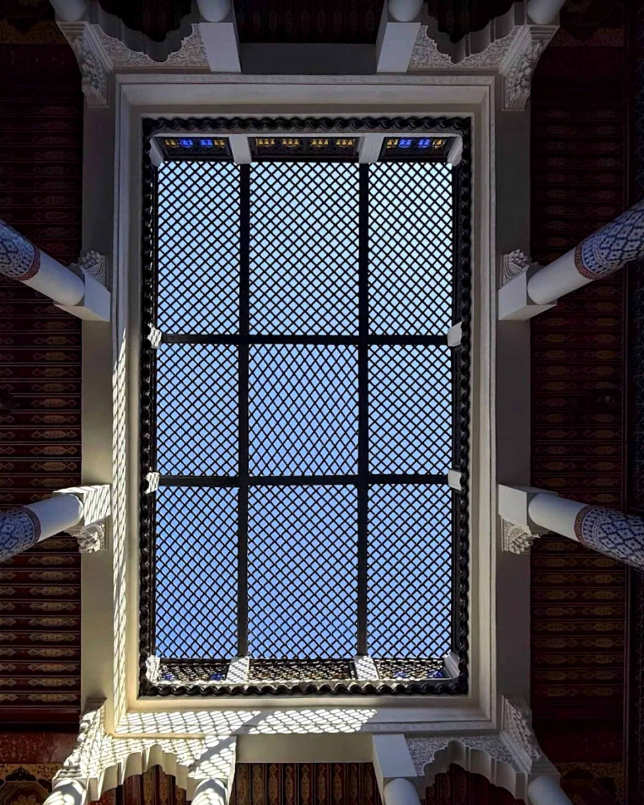 Une fenêtre à carreaux, encadrée d’éléments architecturaux richement décorés.