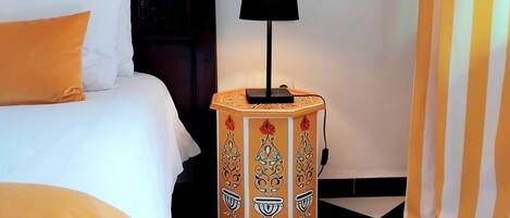 A hotel room with a bed, a nightstand with a lamp, and a checkered floor.