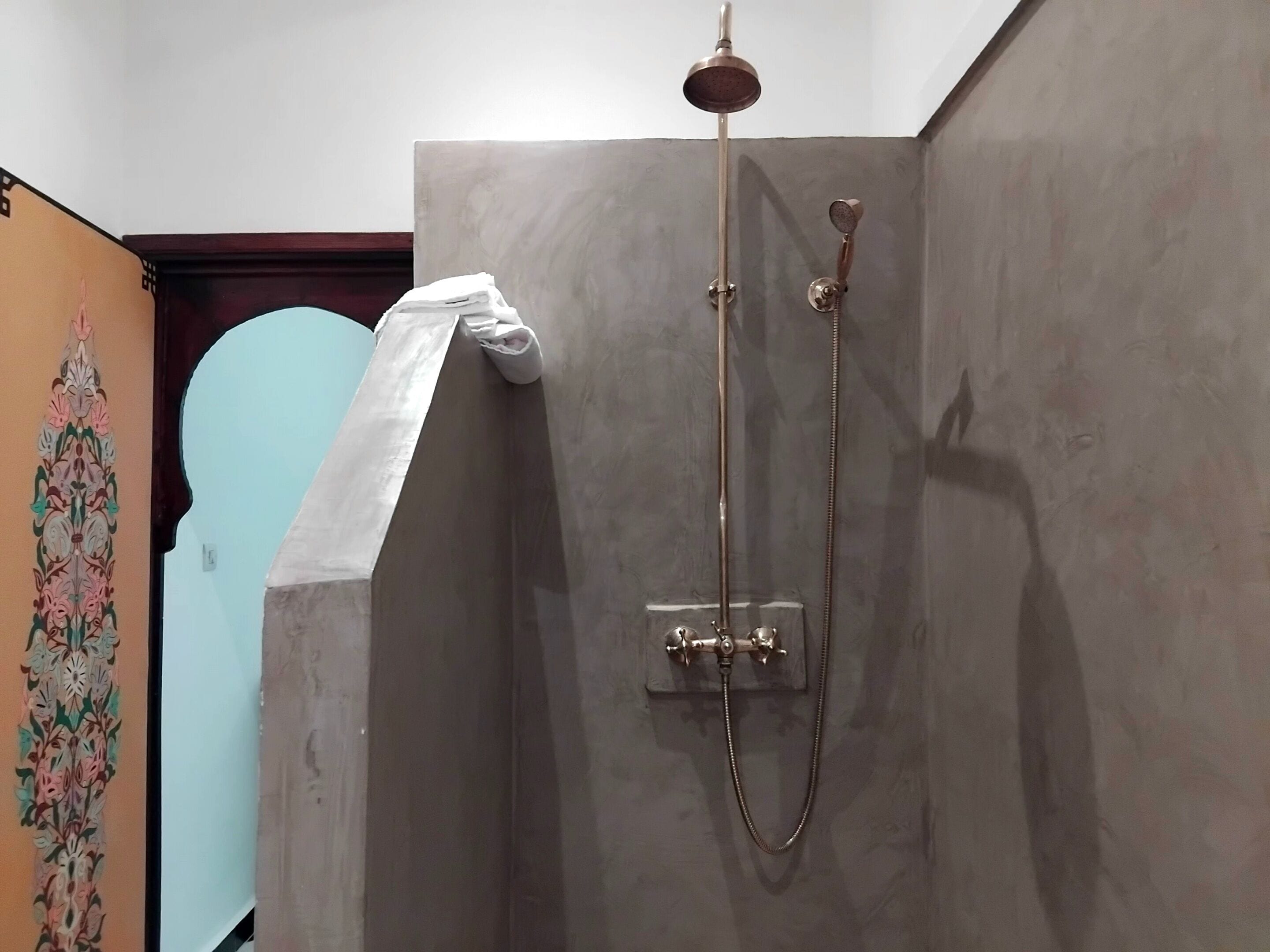 A shower with a handheld showerhead and a wall-mounted faucet.