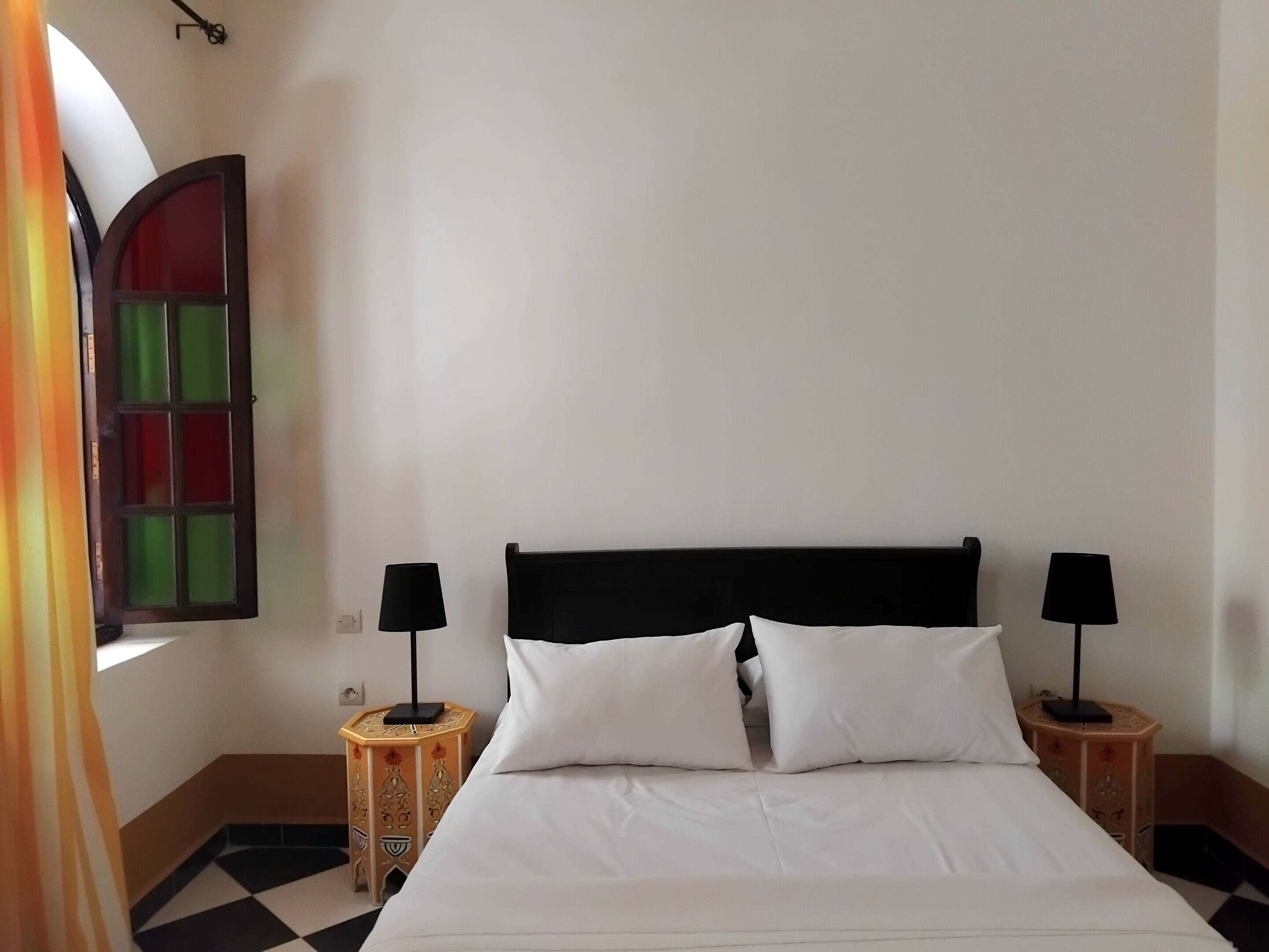 Ein Hotelzimmer mit einem Bett, zwei Nachttischen mit Lampen, einem Fenster mit Aussicht und einer Tür.