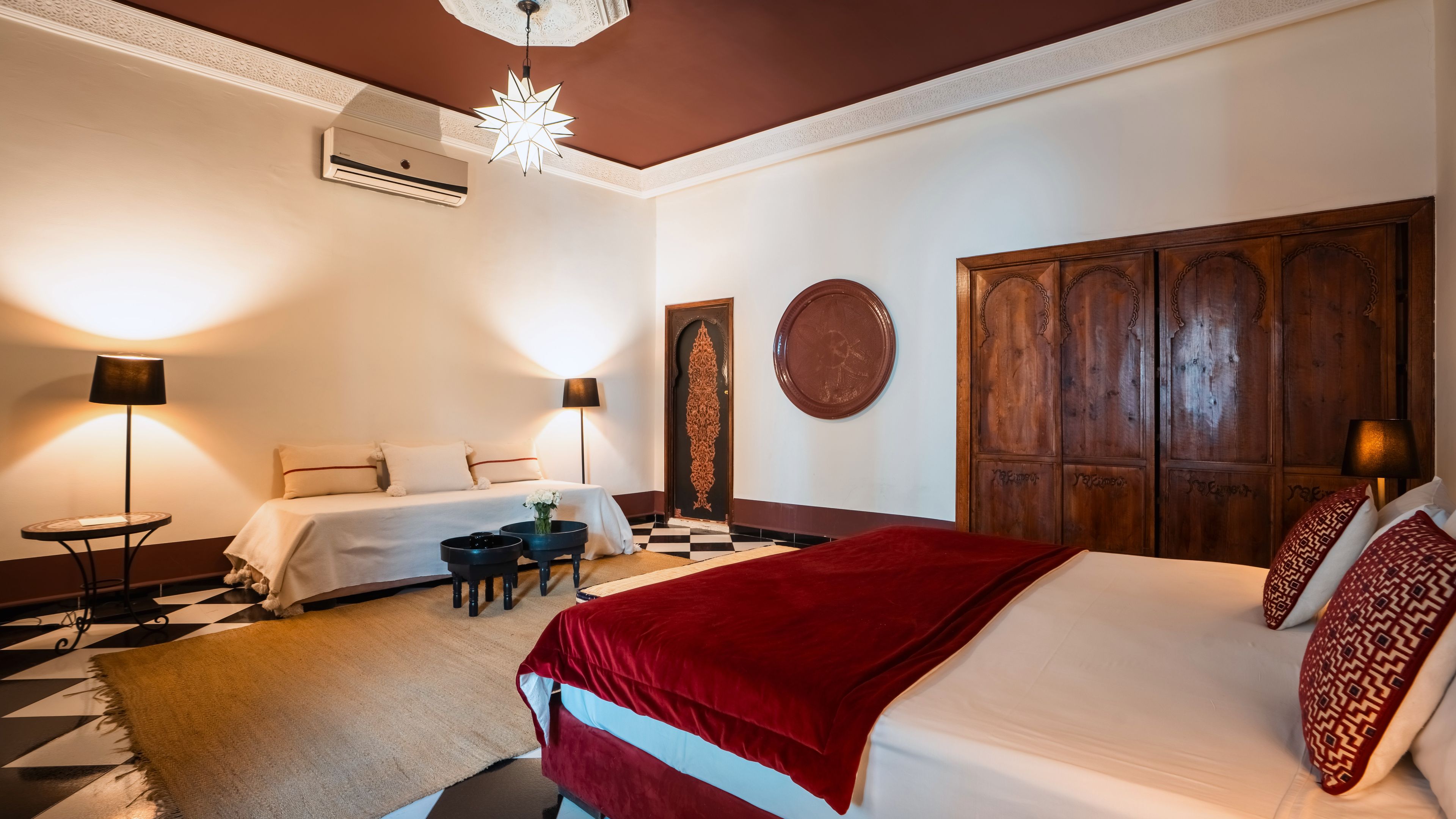A hotel room with a large bed, two bedside tables, a desk with a chair, and a decorative wall panel.