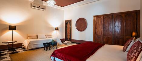 A hotel room with a large bed, two bedside tables, a desk with a chair, and a decorative wall panel.