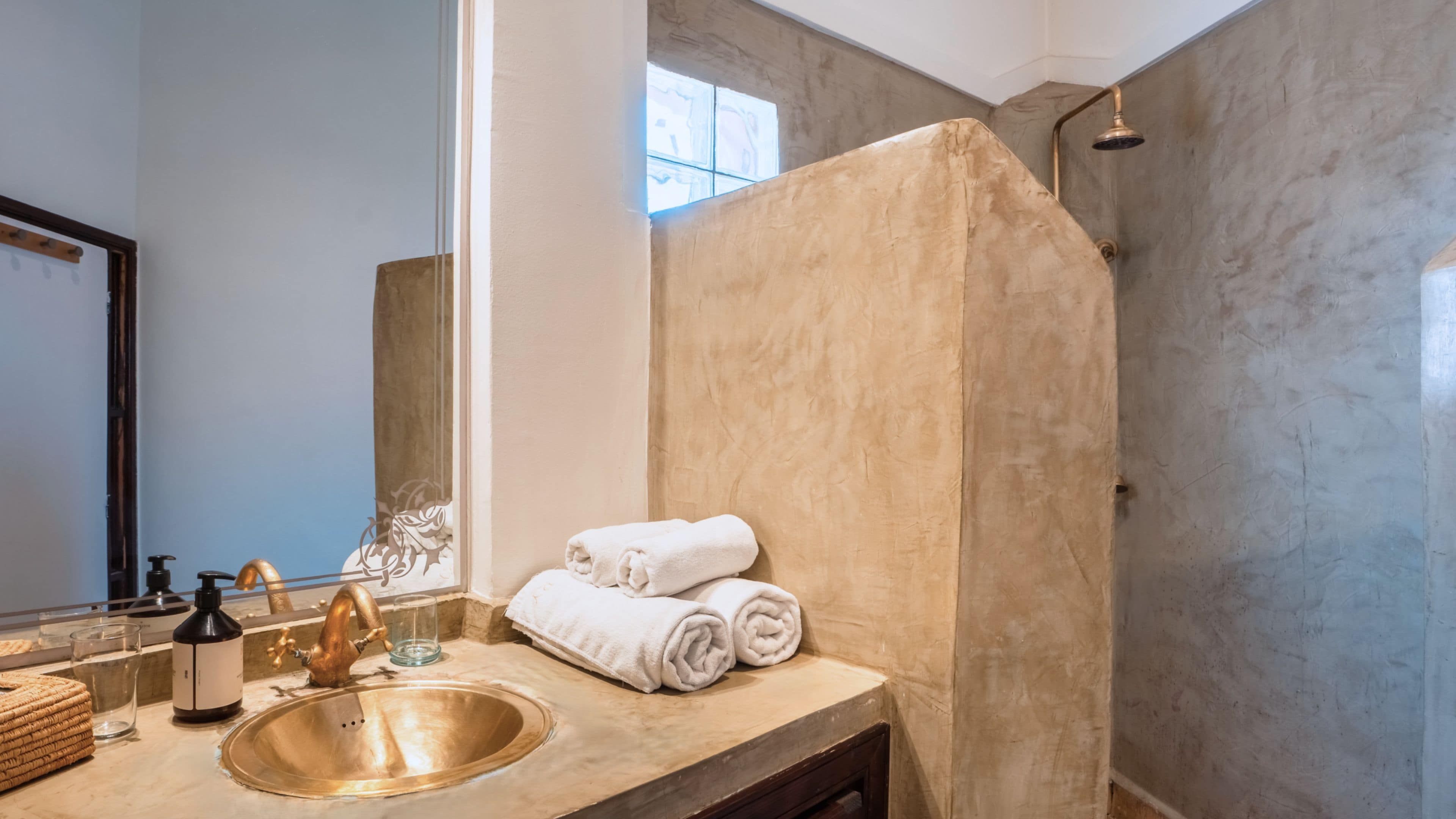 A bathroom with a sink, mirror, and a shower area.