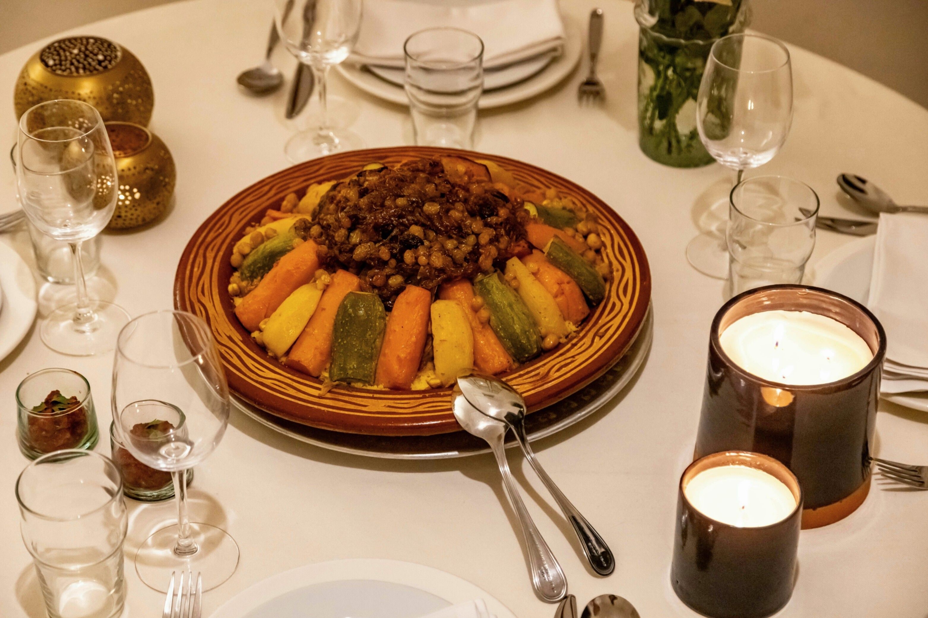 A dining table set with plates, cutlery, glasses, and a candle.