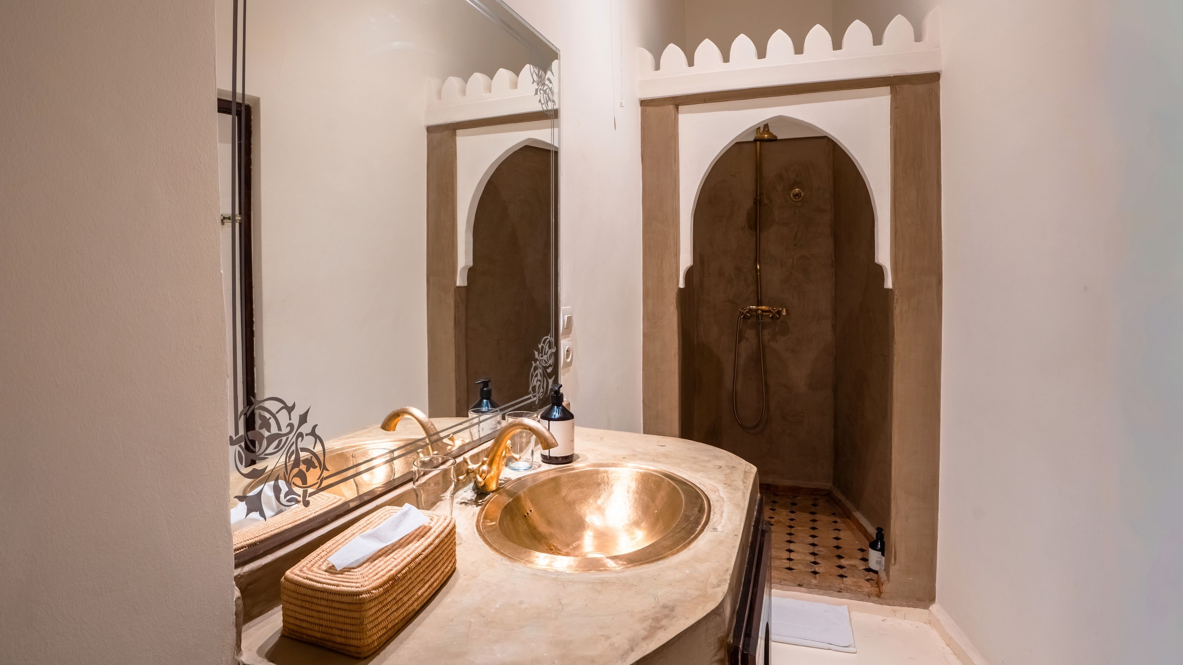 A bathroom with a large copper sink, a mirror, and a shower area.