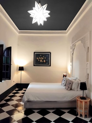 Experience the stylish comfort of this hotel room, featuring a star-shaped ceiling light, a plush bed, and a decorative artwork.