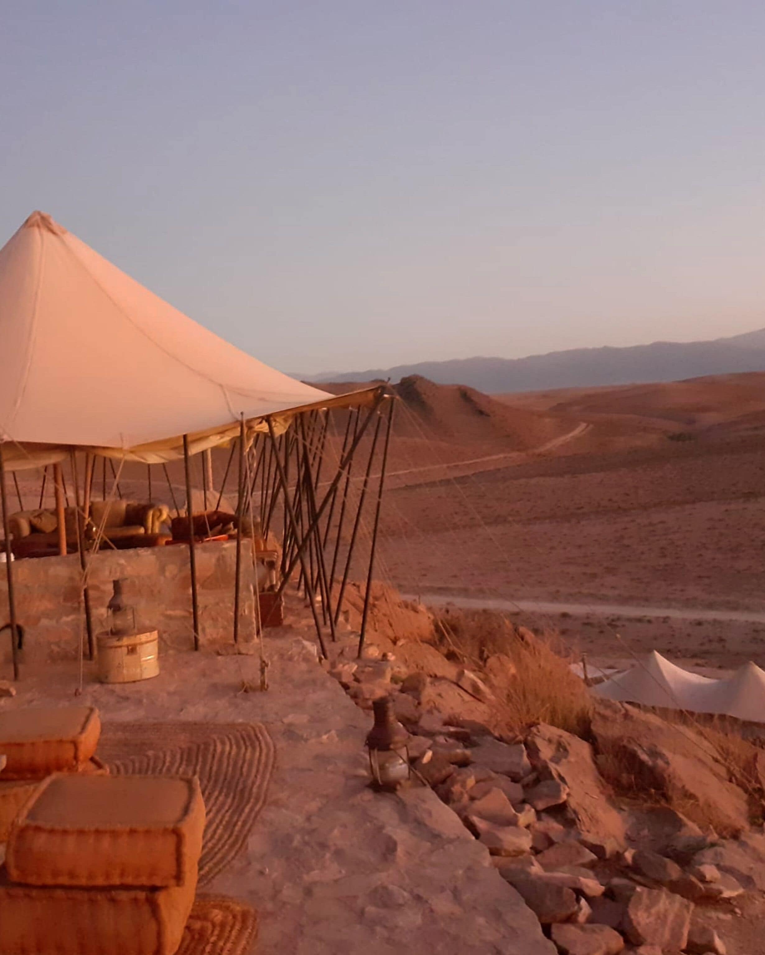A desert tent with a rocky landscape in the background.