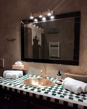 A bathroom with a checkered floor, a large mirror, a sink, and towels.