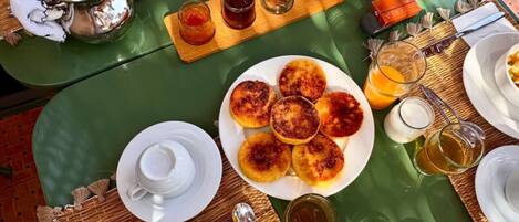 Ein Frühstückstisch mit verschiedenen Speisen, darunter Pfannkuchen, Obst und ein heißes Getränk.