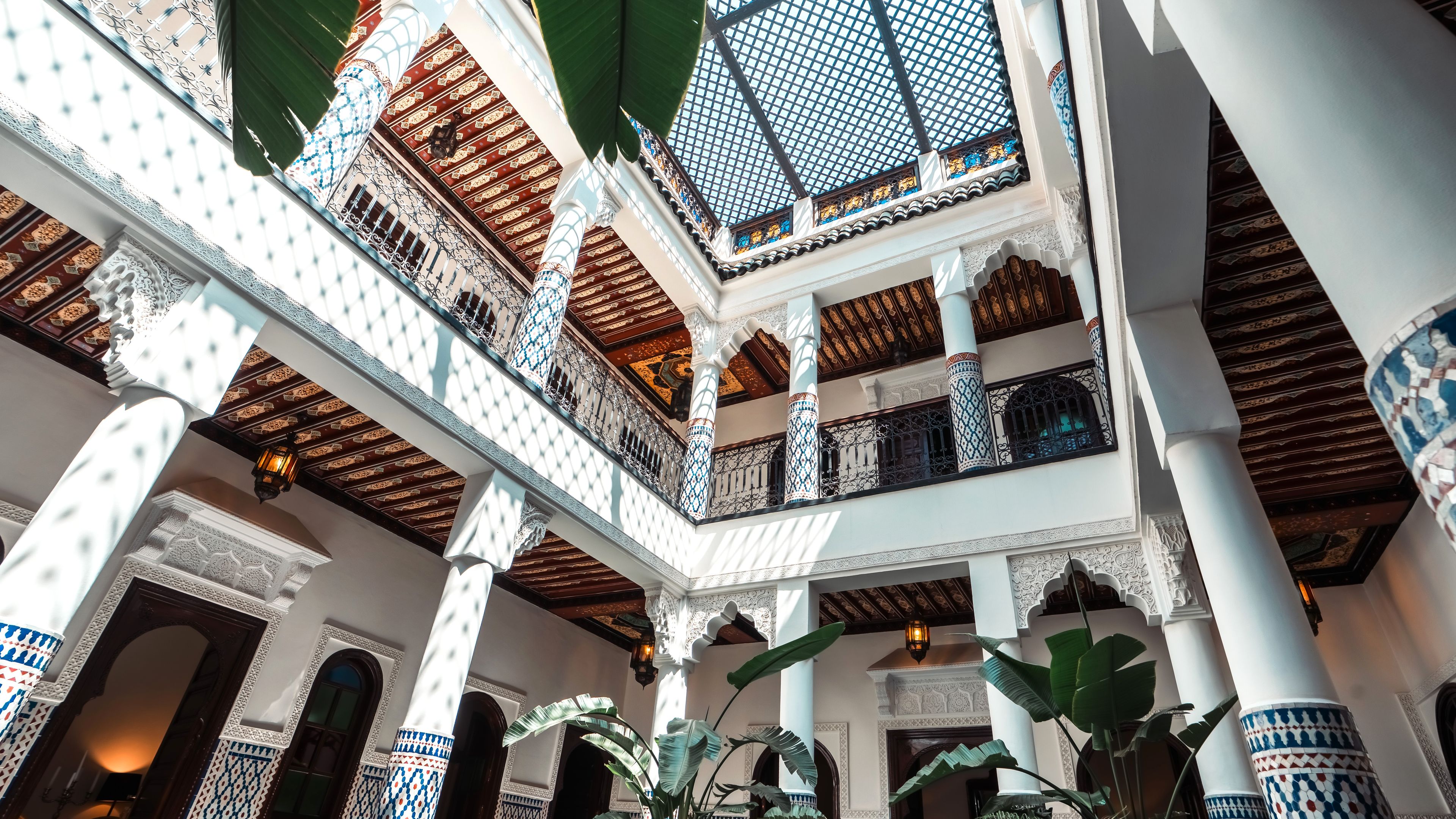 A multi-level atrium with ornate columns, patterned railings, and a skylight.