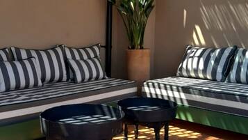 Un coin salon confortable avec des coussins à rayures, une plante en pot et une petite table.