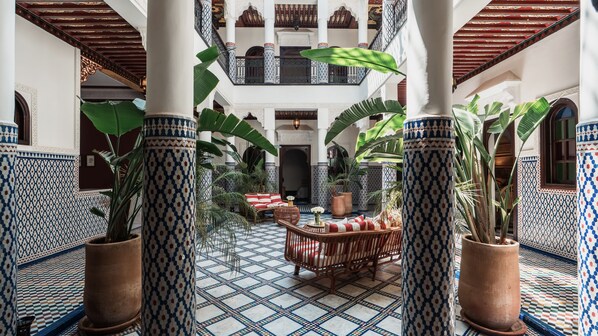 A courtyard with tiled flooring, a seating area, and large potted plants. - Riad Yakimour (Marrakech)