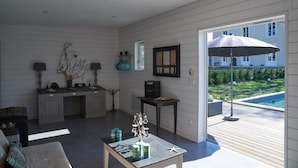Un amplio salón con vista a la piscina, un comedor con mesa y sillas, y una cocina con armarios y estufa.