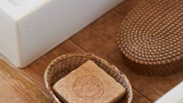 A wooden table with a woven basket containing a soap bar, a woven mat, and a white appliance.