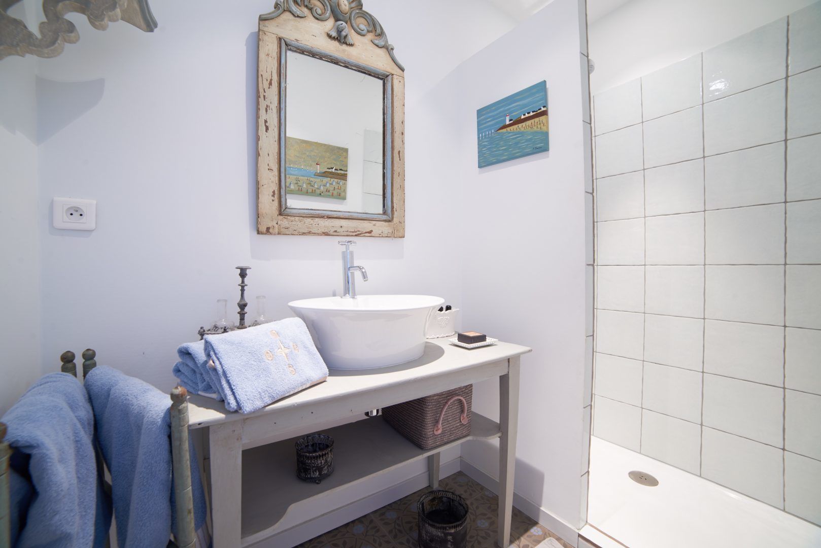 Un baño con lavamanos blanco, espejo y zona de ducha.