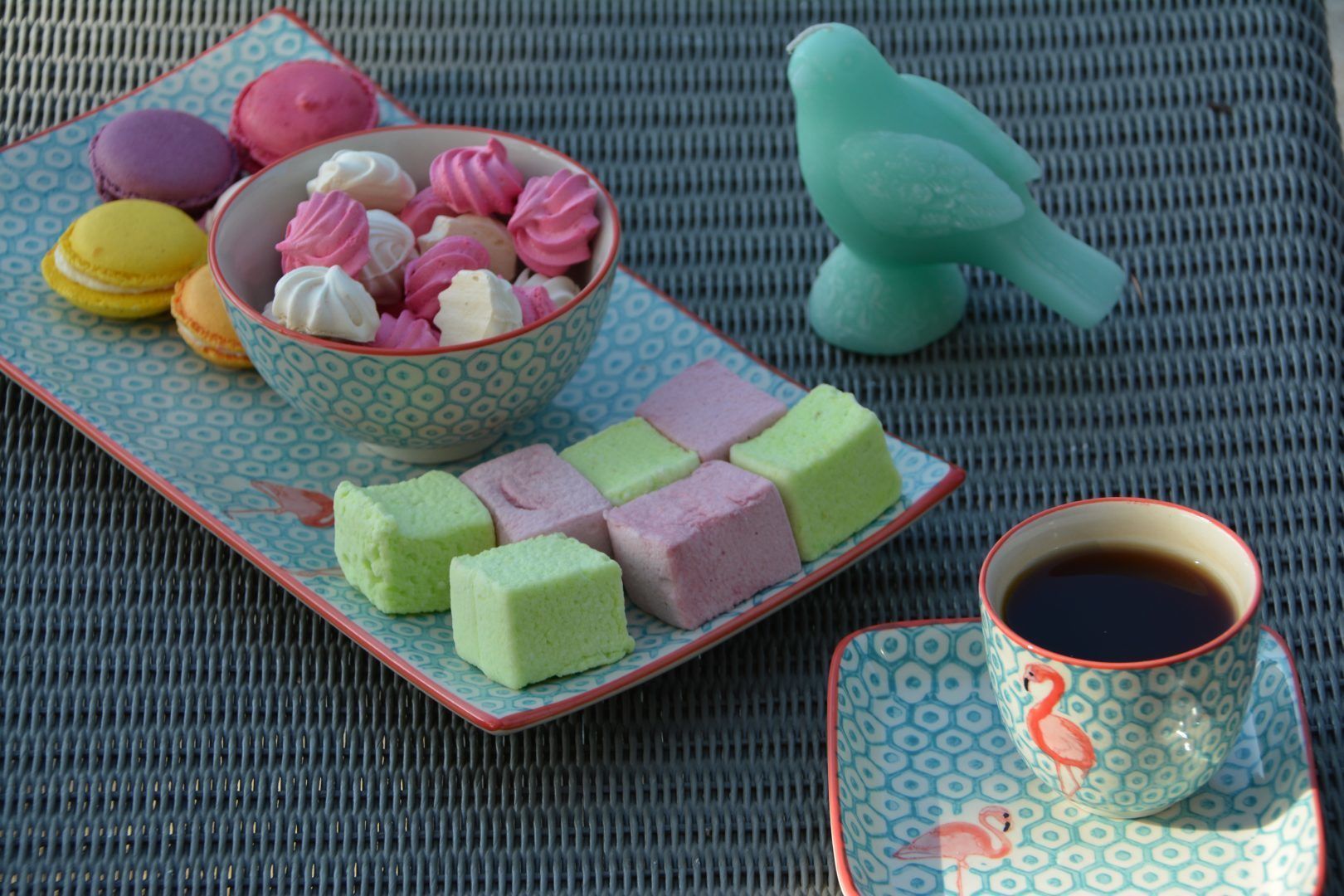 Un safataix amb macarons de colors, mochi, una decoració amb forma de parell i una tassa de te sobre un estovat de fibra.