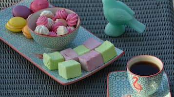 Un safataix amb macarons de colors, mochi, una decoració amb forma de parell i una tassa de te sobre un estovat de fibra.