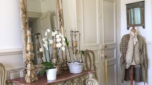 Un tocador de estilo antiguo con elaboradas tallas, un espejo grande y una orquídea en maceta.
