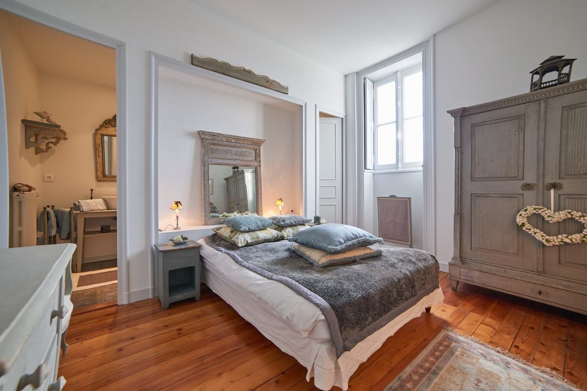 Een slaapkamer met een groot bed, een kaptafel, een dressoir en een garderobe.