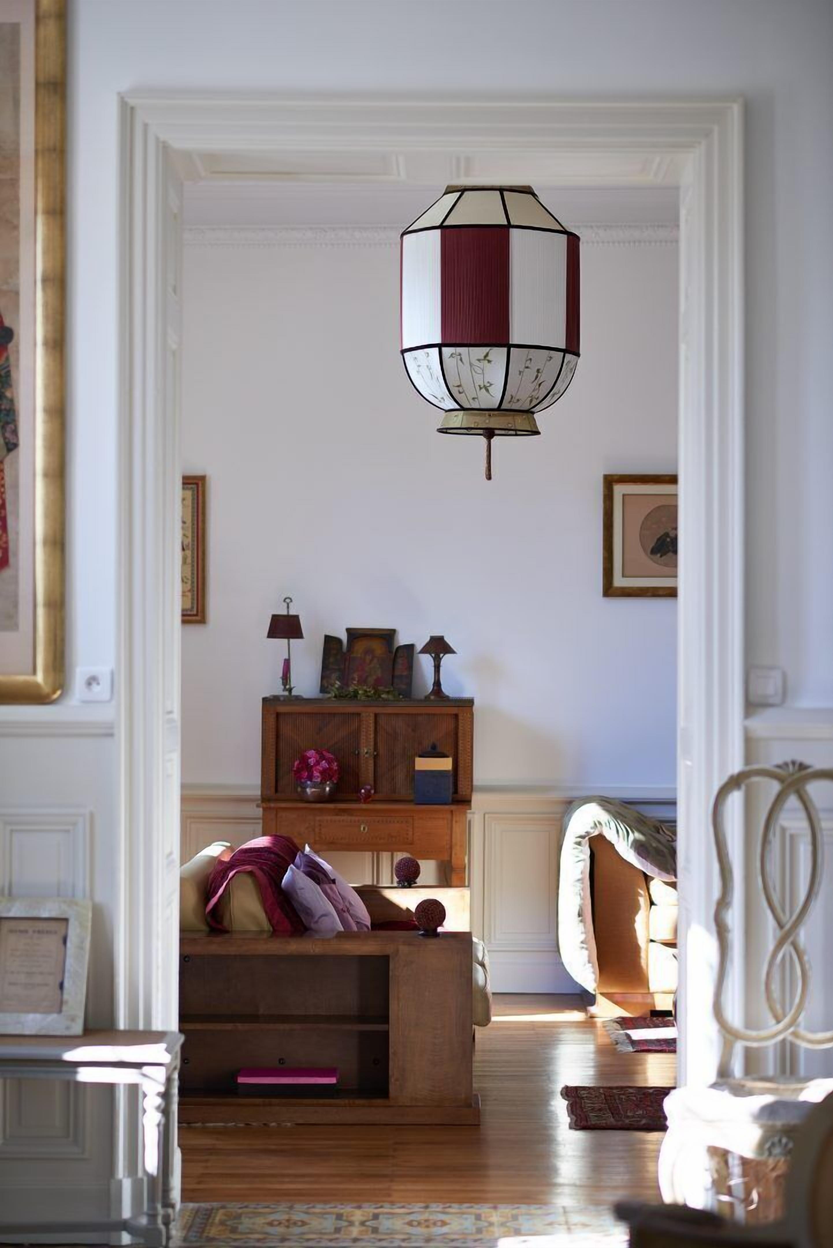 Una habitación con un armario de madera, una lámpara colgante y un tapete estampado.