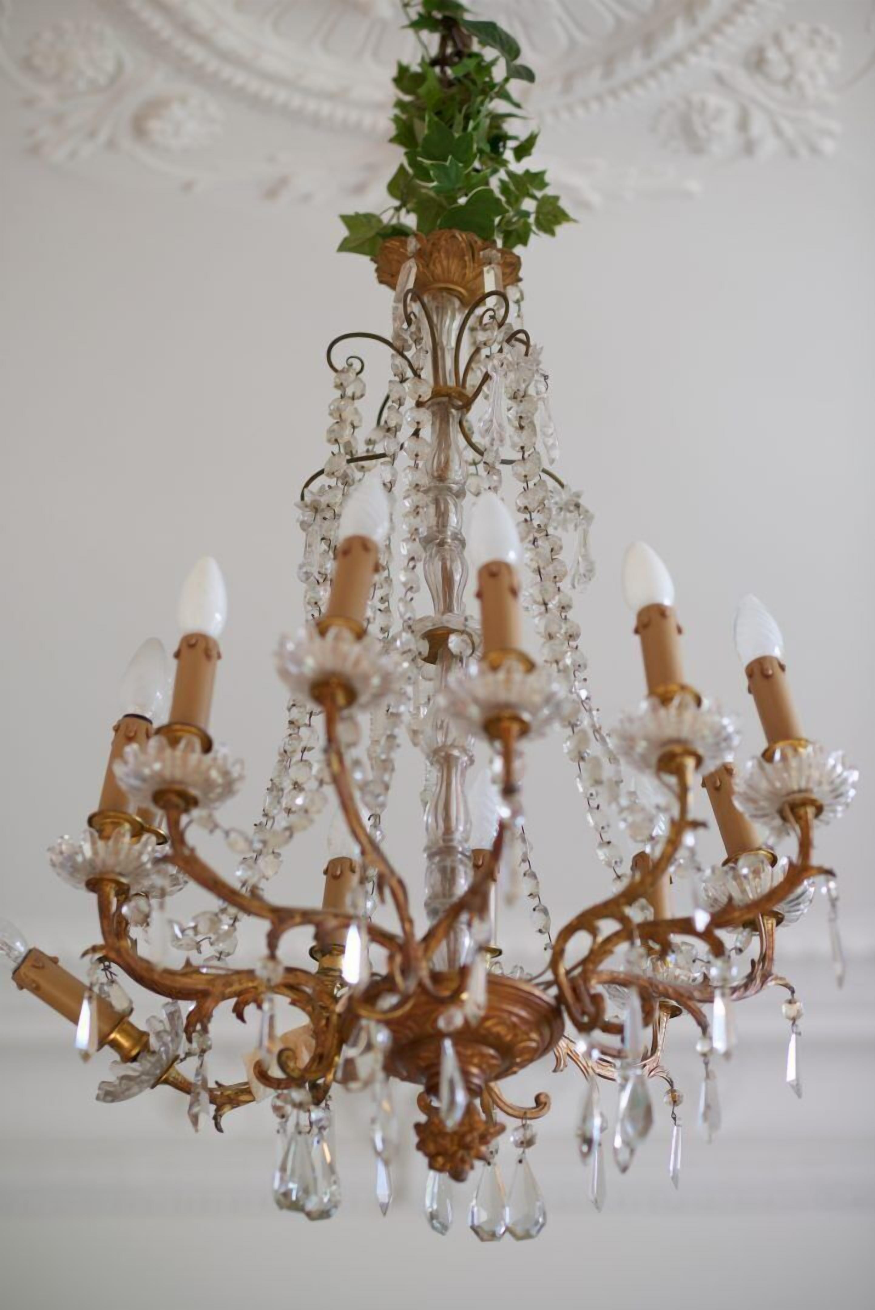 Un lustre orné de nombreuses lampes en forme de bougies et de décorations en cristal.