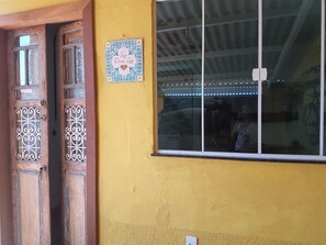 A yellow wall with a window and a door. - Casa Acolhedora no Paraíso (Arraial do Cabo)