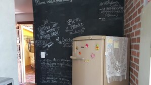 A kitchen with a refrigerator covered in magnets and a chalkboard with handwritten notes.