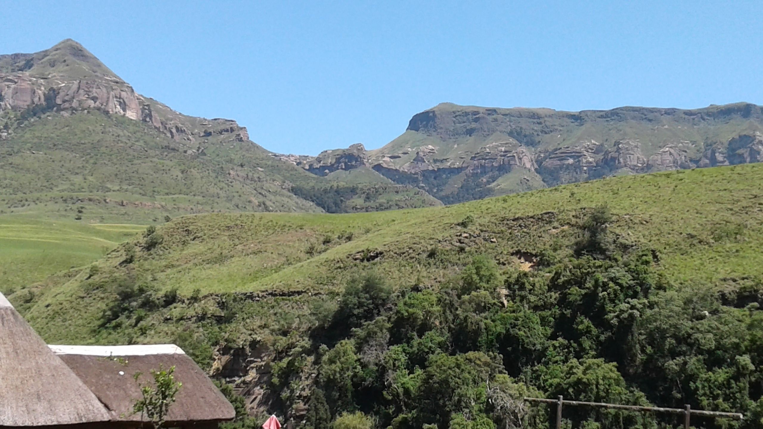A mountainous landscape with a thatched-roof hut in the foreground.