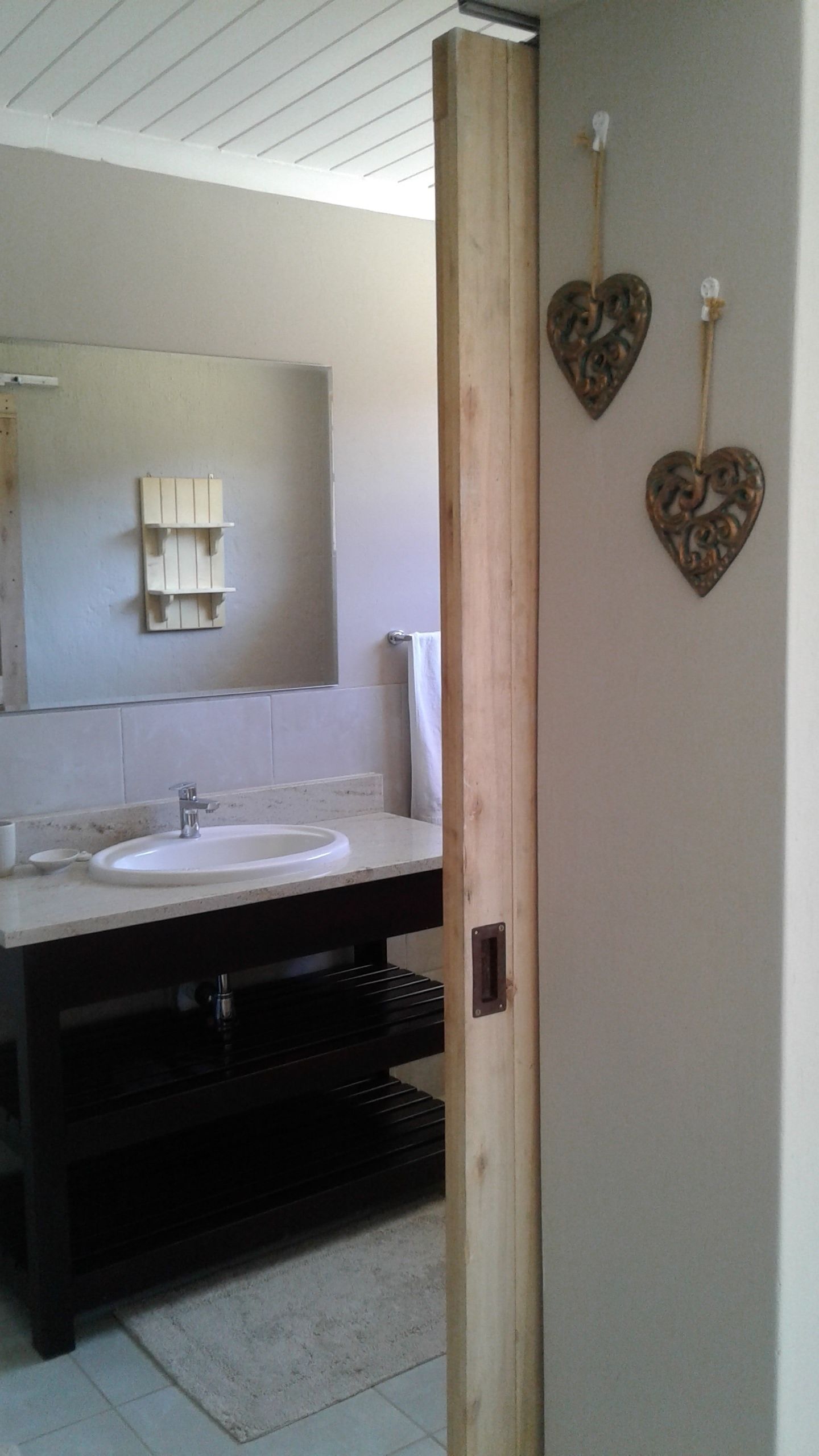 Un bany amb un lavabo blanc, un mirall i un penjallotges de tovalloles.