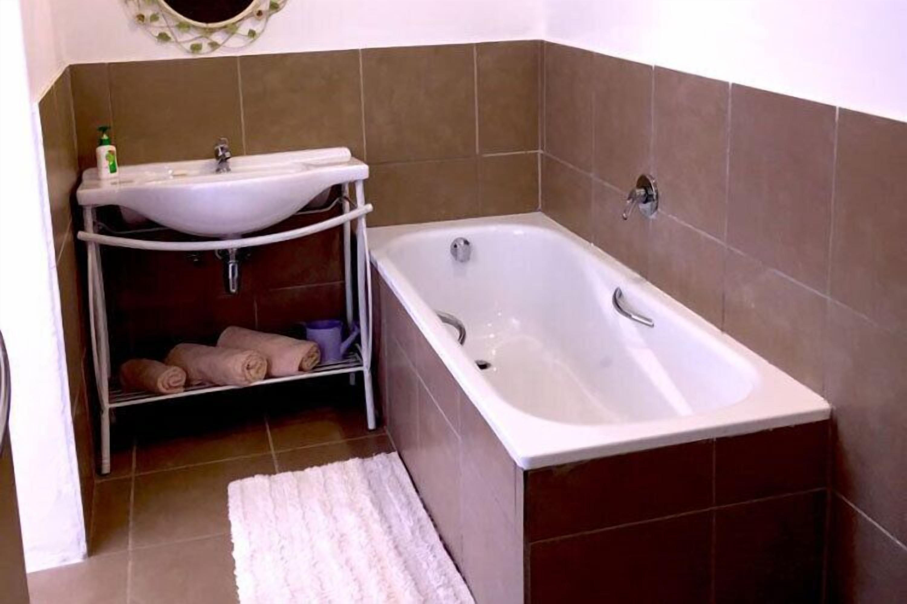 A bathroom with a white bathtub, a white sink, and a towel rack with towels.
