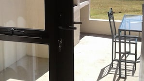 A balcony with a table and chairs, overlooking a mountainous landscape. - Ledges Retreat (Jagersrust)