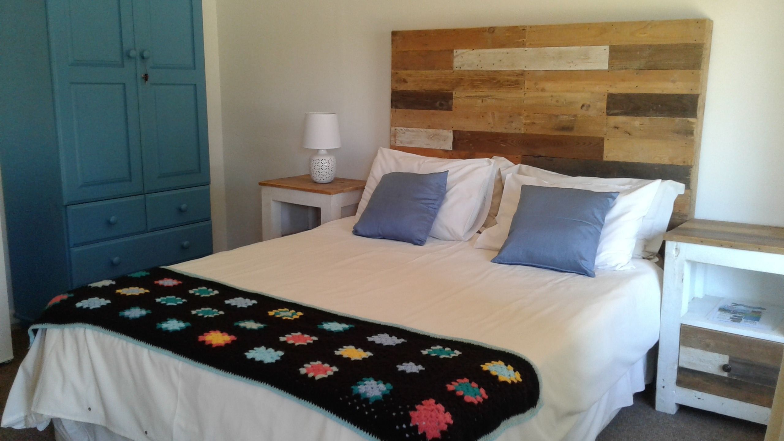 A bedroom with a bed, a nightstand, a lamp, and a wardrobe.