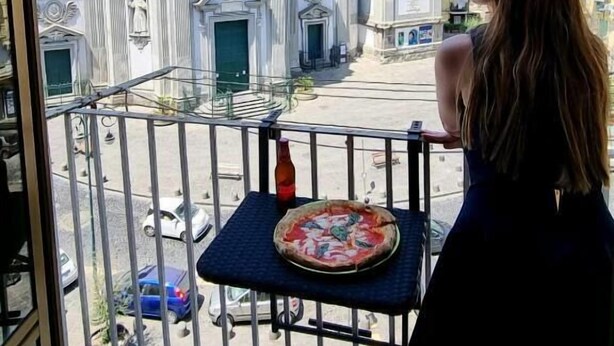 A balcony with a table holding a pizza, overlooking a historic church with a dome and bell tower. - Andrea's House Apartment in the Historic Center of Naples (Naples)